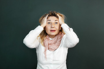 Omg. Studio shot of terrified middle aged female staring at camera with mouth opened, tearing hair out, feeling shocked or stressed, being completely lost, responding to bad negative news or problem