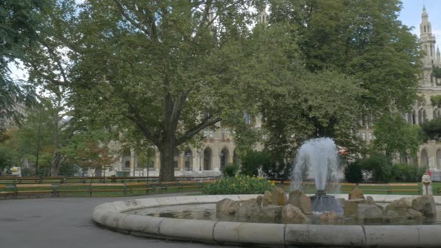 Pan of fountain in Rathaus park in Vienna, Austria. Tower of Rathaus on the background