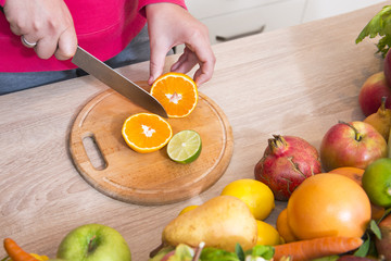 Slicing tangerine with knife on kitchen board