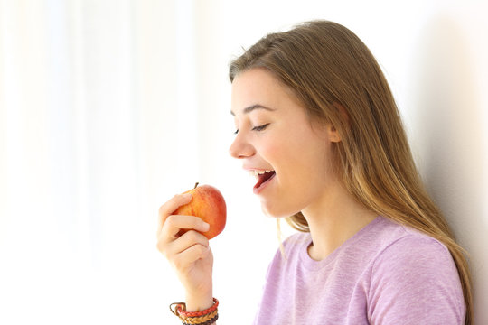 Teen eating an apple isolated on white at side