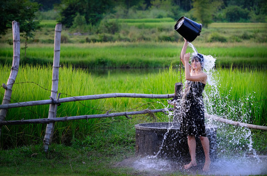 Rural girl is taking a shower from a traditional Groundwater at countryside.
