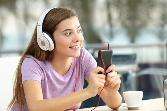 Happy teen listening to music in a coffee shop