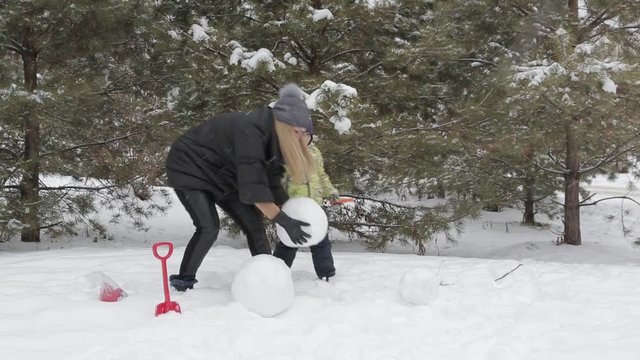 Mom and son make a snowman 2 Happy mother and son make a snowman falling fluffy snow