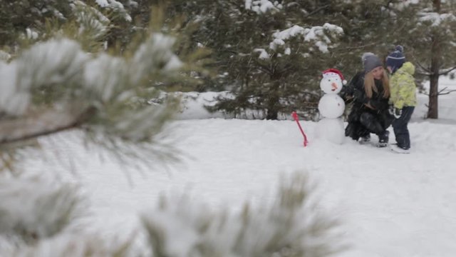 Mom and son make a snowman 13 Happy mother and son make a snowman falling fluffy snow