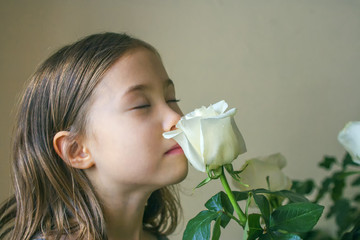 Six-year old girl with closed eyes enjoying the scent of white roses