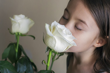 Six-year old girl with closed eyes enjoying the scent of white roses