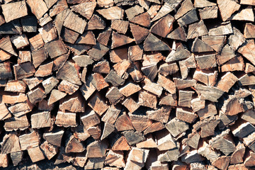 Stack of natural firewood in preparation for the winter and used for camp fires, fireplaces and home heating. Chopped and piled wood background texture.