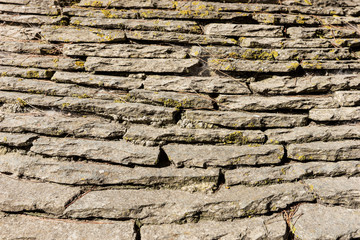 Layered natural stone wall with moss, stone wall background