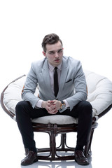 tired businessman sitting in a round chair made of rattan