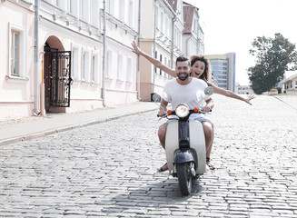 Happy young couple having fun on a scooter - obrazy, fototapety, plakaty