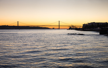 Fototapeta na wymiar Large panoramic view of Amazing sunset on Ponte 25 de Abril Bridge, (25th of April Bridge) at Lisbon. Portugal