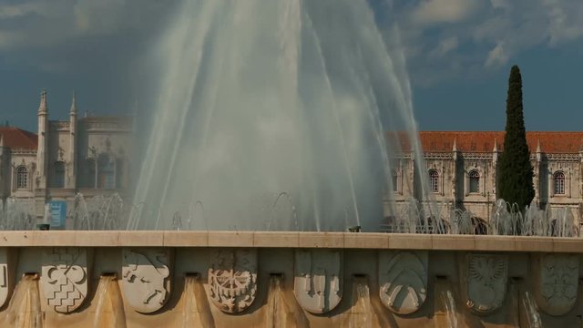 Telephoto shot of a water fountain in Praca do Imperio square opposite the 16th century Hieronymites Monastery, Mosteiro dos Jeronimos, in Lisbon, Portugal.
