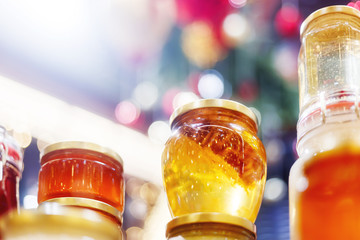 Holiday fair. Jars of honey glowing in garlands of lighting bulbs.