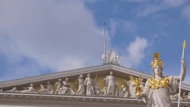 Short pan from left to right of top of parliament building and Athena statue in Vienna