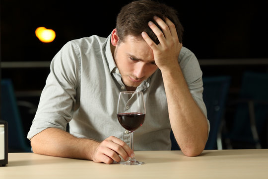 Sad man drinking wine in a bar