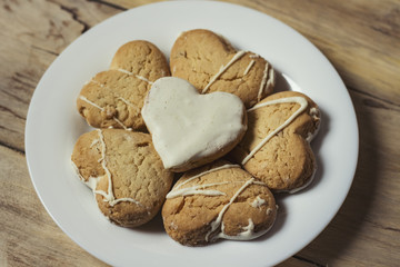 Cookies in the form of hearts on a white plate, on a wooden table. Flat lay. Close-up