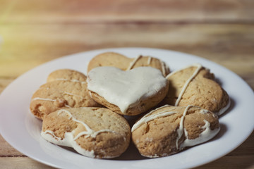 Cookies in the form of hearts on a white plate, on a wooden table. Close-up