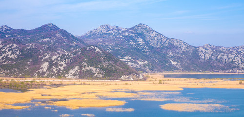 mountains with snow and blue water with yellow grass