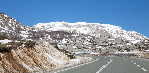 smooth highway to snow-covered mountain in sunny day