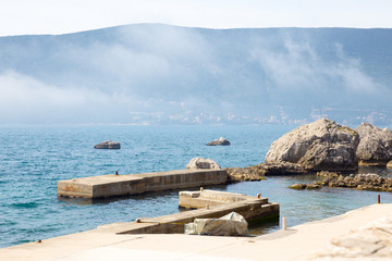 old pier, stone, sea and mountain in fog