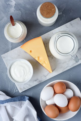 Selection of dairy products on marble background. Eggs, Cheese, Milk, Yogurt, Sour cream and Cream. Top view