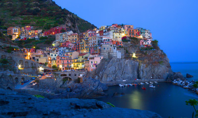 Fototapeta na wymiar Manarola, Liguria, Italy. Beautiful wonderful village as you can see it from the mountain above. Quiet sky and peaceful sea, during sunset background.