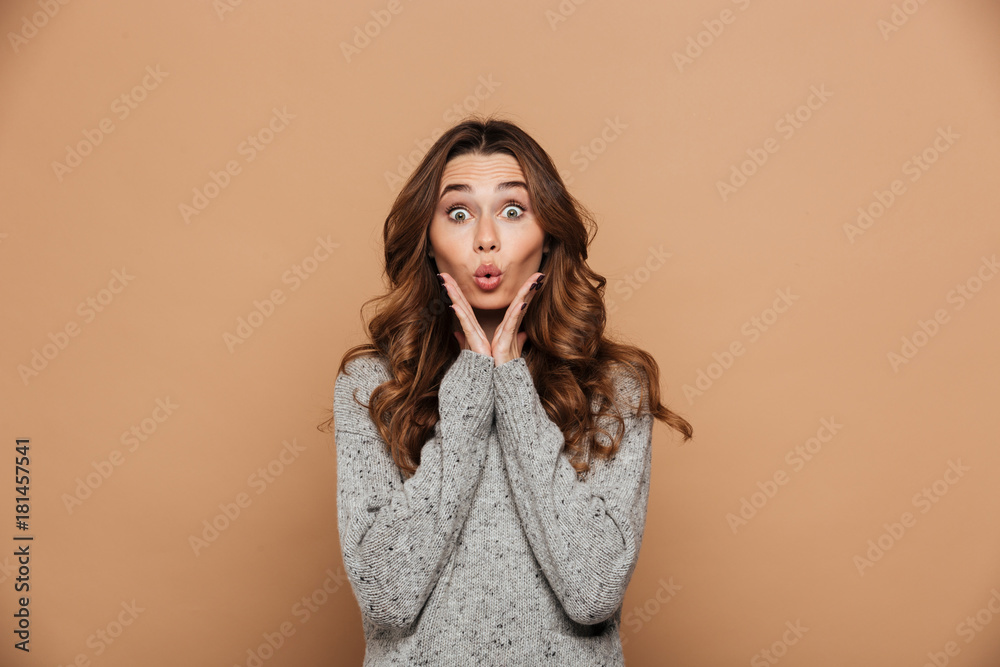 Canvas Prints Amazed pretty woman in gray knitted sweater touching her face, looking at camera