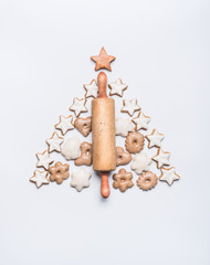 Fototapeta na wymiar Christmas tree made with rolling pin, cookies and gingerbread on white background, top view. Festive layout or pattern for greeting card
