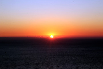 Fototapeta premium The red sunset sky with the sun and clouds. Beautiful and colorful sunset sky. Oia Santorini Greece