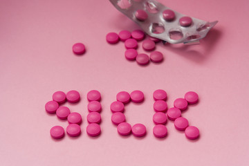 Obraz na płótnie Canvas Pink pills on a pink background. The word 