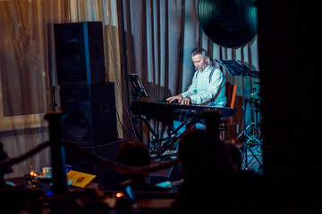A man of European appearance, a musician, plays a synthesizer.
