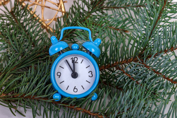 Christmas fir tree branches with alarm clock on rustic wooden background with copy space