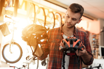 A young man looks closely at the helmets for bicycle rides.