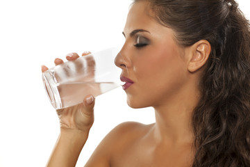 a young woman drinks cold water from the glass