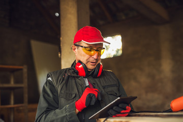 Modern professional fabric worker with protection holding a tablet and checking status of production.