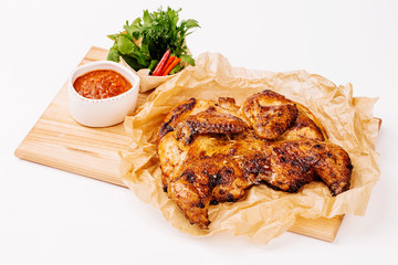 Grilled chicken Tabaka with sauce on a plate on white background for menus.