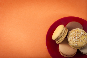 Delicious french cake dessert and pastry concept with colorful biscuit cookie called macaron on orange background with copy space