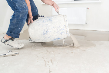 Worker pouring concrete on the floor in the room. Fill screed floor repair and furnish
