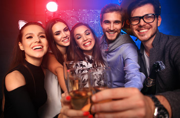 Enjoying amazing party. Group of beautiful young people dancing with champagne flutes and looking happy.