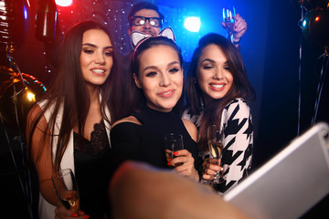 party, technology, nightlife and people concept - smiling friends with smartphone taking selfie in...