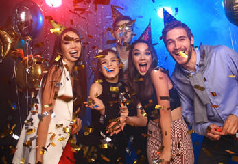 Cheerful young people showered with confetti on a club party. - obrazy, fototapety, plakaty