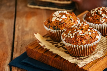Carrot cake muffins with nuts, raisins and oats on a wooden background.