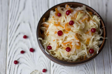 sauerkraut with cranberries in a clay plate on a wooden table