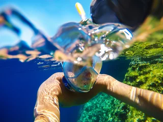 Tuinposter Underwater close surface split photo of a young playful man with a snorkelling mask swimming in the turquoise exotic sea for summer vacation. © dusanpetkovic1