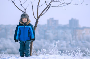 Funny little boy standing under the tree
