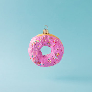 Christmas bauble decoration made of pink doughnut. Minimal New year concept.
