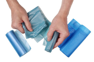 An elderly man tears off a blue plastic garbage bag from a whole roll