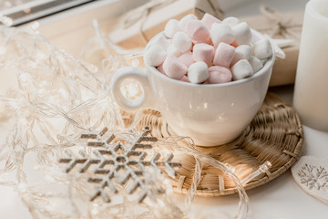 Cup of hot chocolate and marshmallow in the background of Christmas decorations.