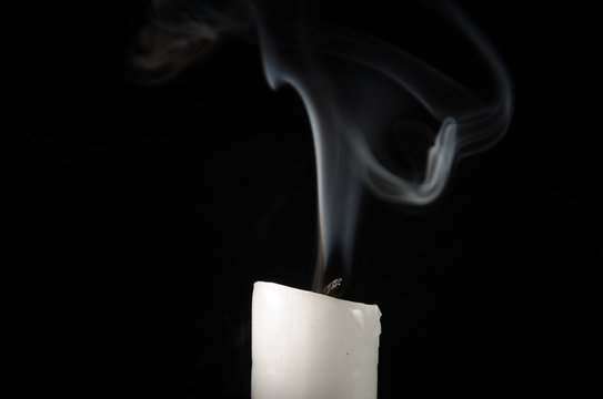 Burning Candle With Fading Flame And Smoke On A Black Background