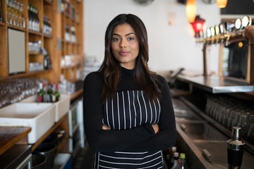 Beautiful waitress standing with arms crossed in bar